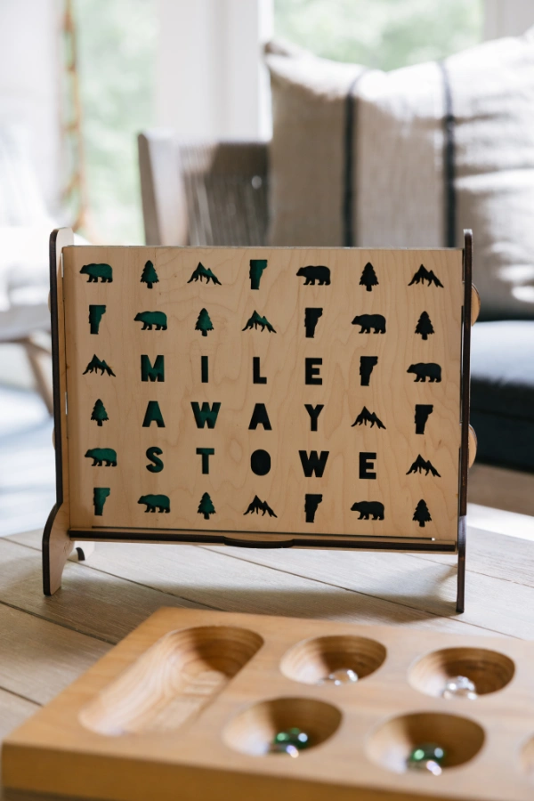 Close-up of custom wooden game board and decorative sign on coffee table, styled for casual indoor entertainment